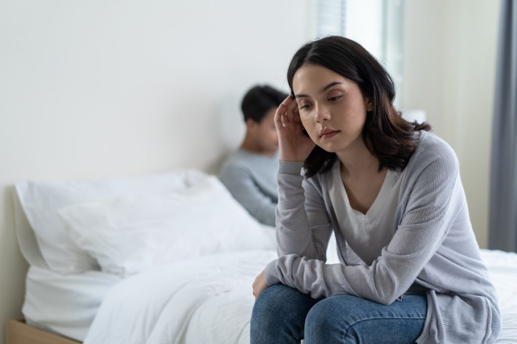 frustrated woman sitting on the side of bed