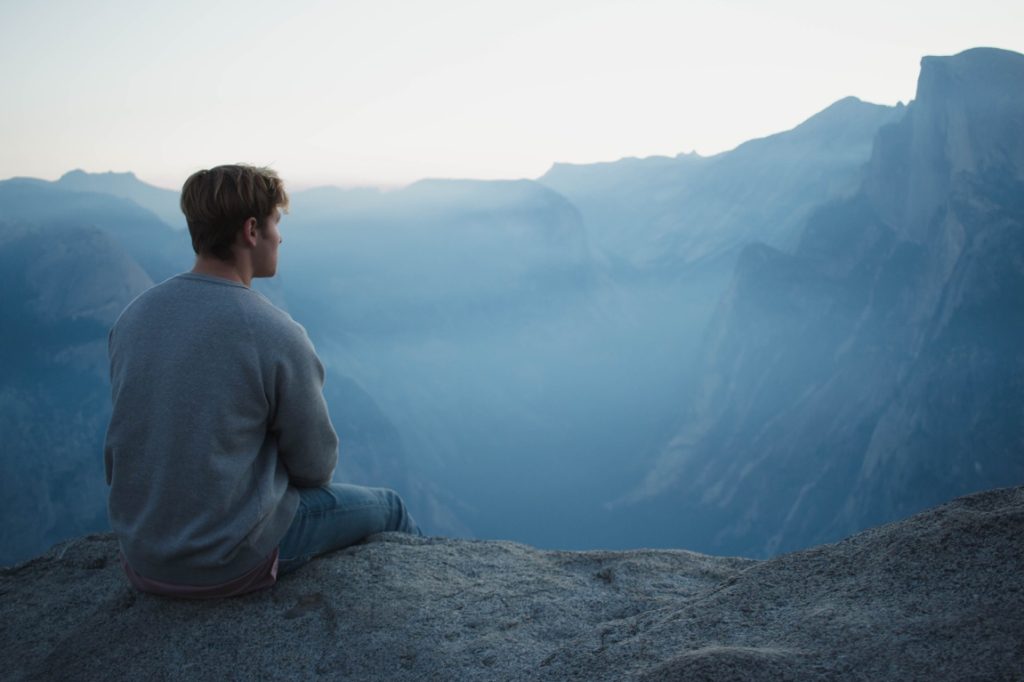 man sitting on top of a mountain