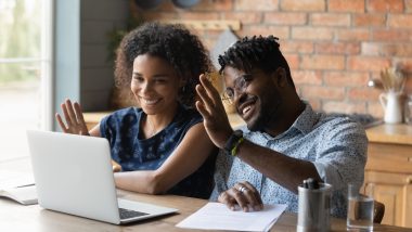 couple waving hands in front of laptop