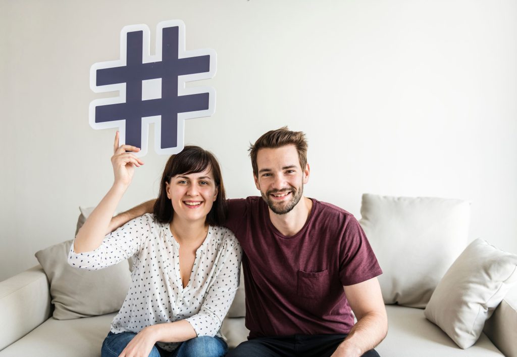 man and woman holding a hashtag sign