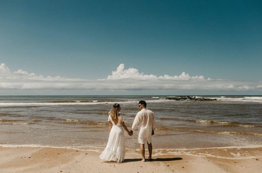 newlyweds holding hands in front of the beach