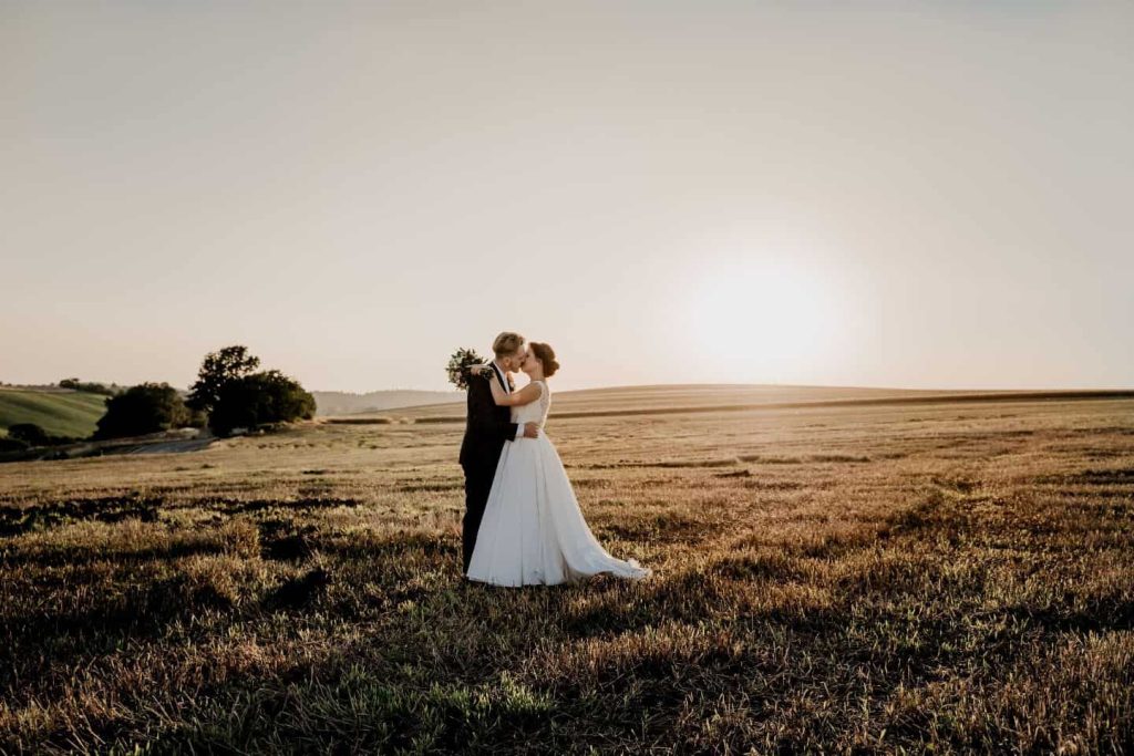 newlyweds kissing on a field