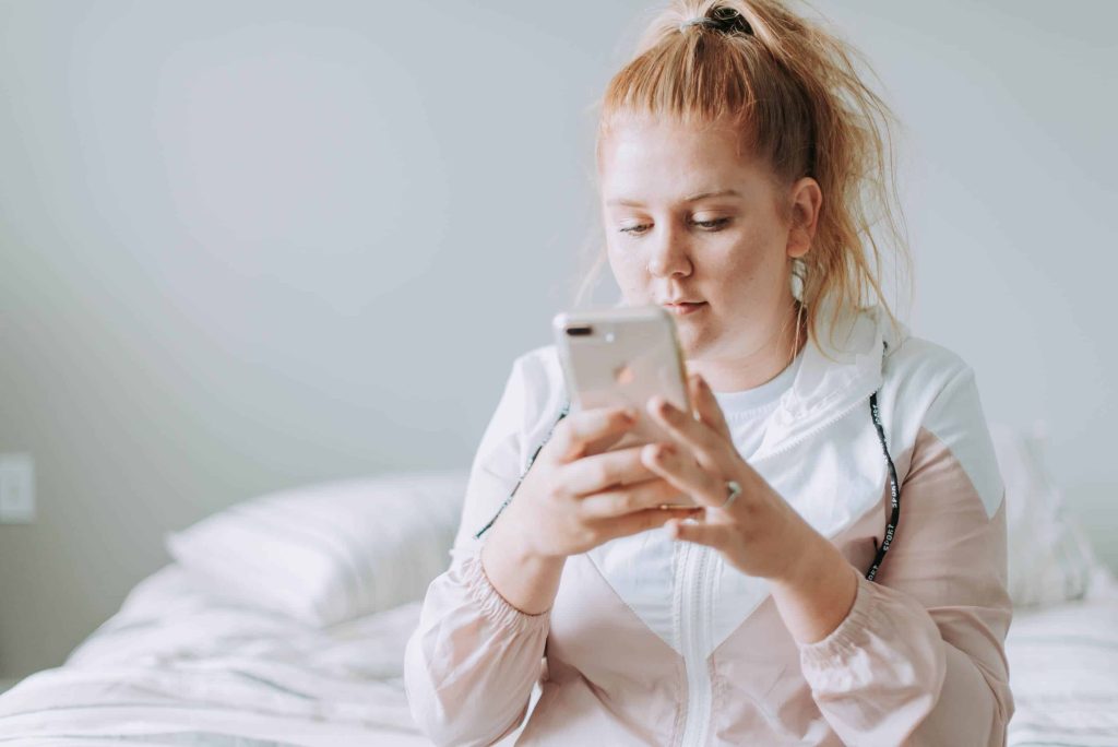 woman sitting in bed while texting