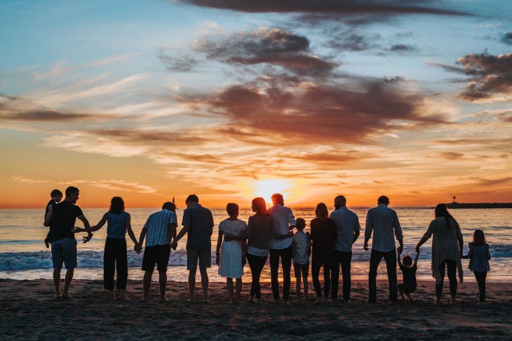 a large family facing the sunset at a beach
