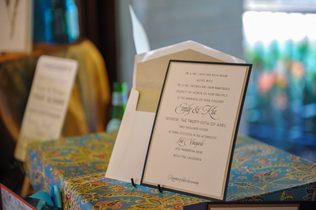 a wedding invitation and envelope propped up on a paper stand