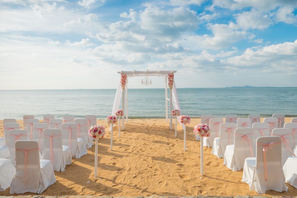 beach wedding with rows of chairs and wedding arch facing the sea