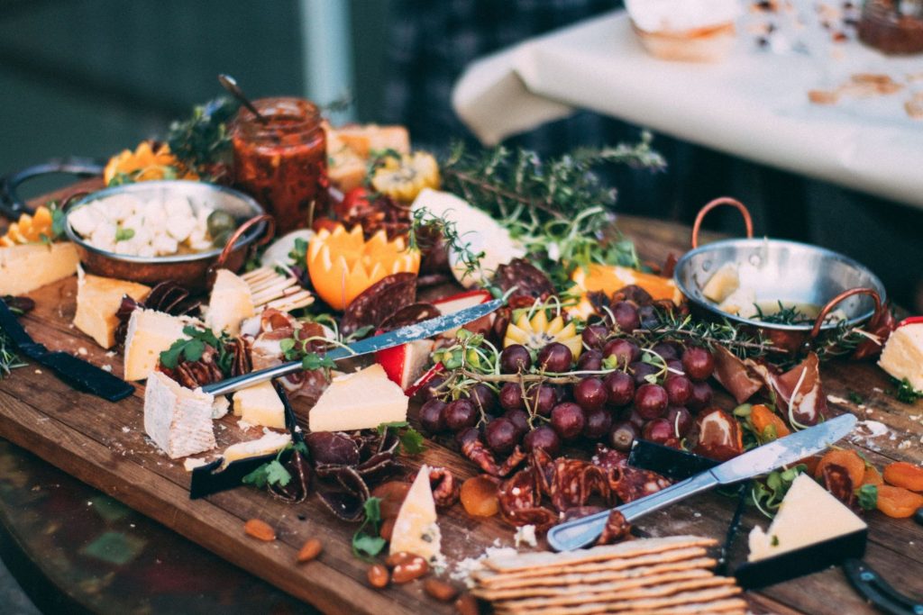 charcuterie board with various cheese, dips, grapes, and more