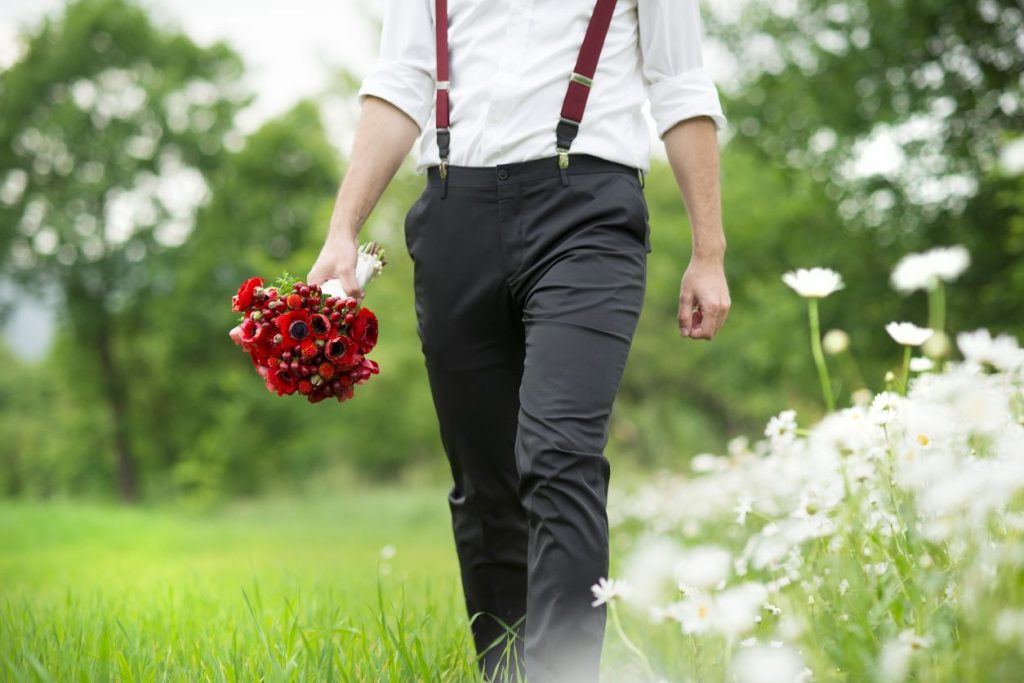 man in suspenders holding a bouquet