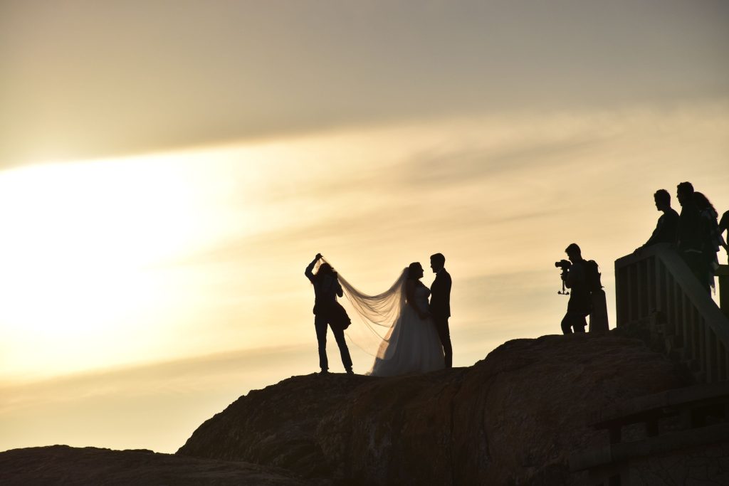 silhouettes of a photography team taking photos of a couple during sunset