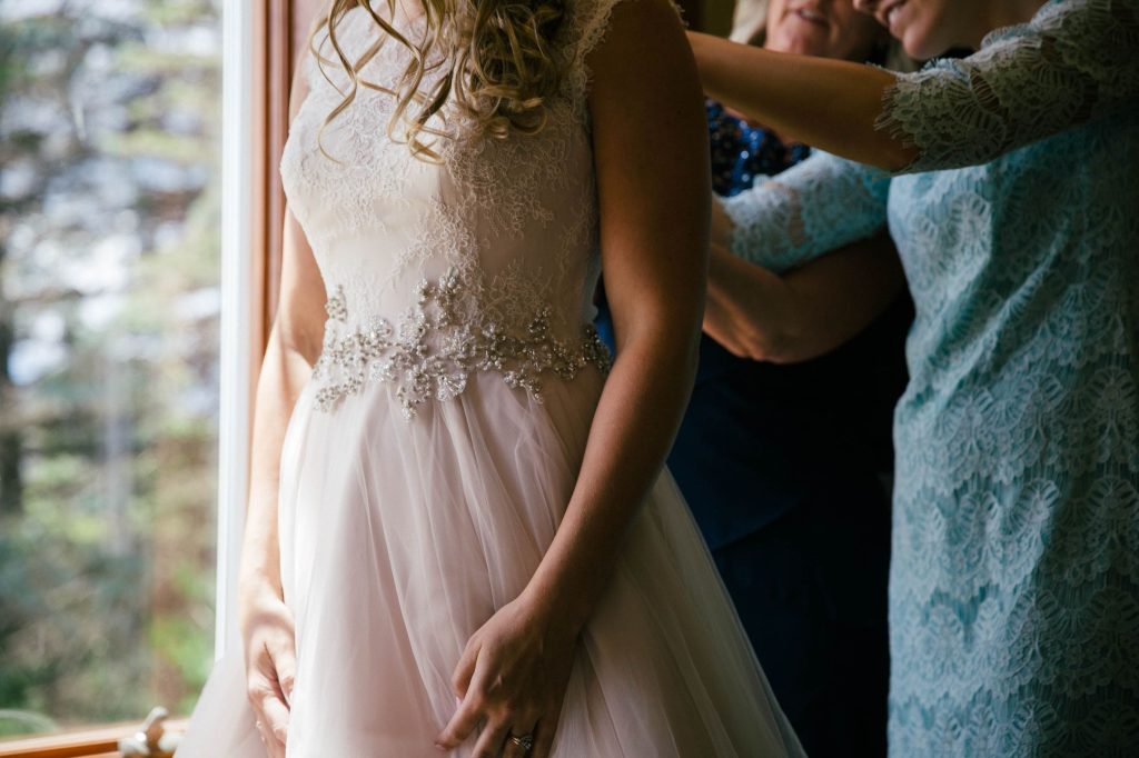 woman buttoning up bride's dress
