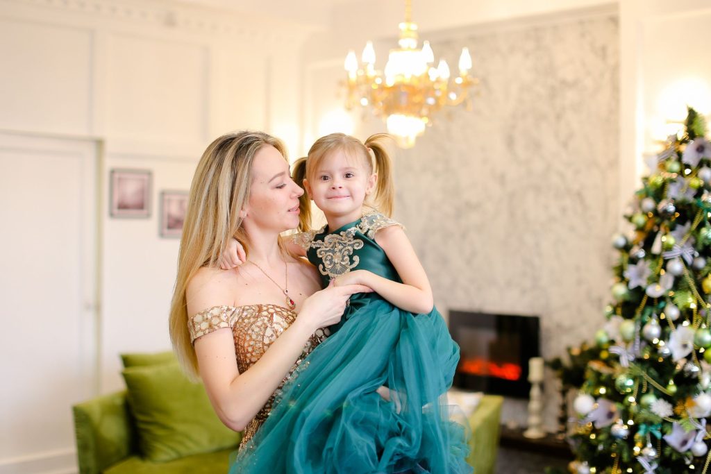 woman carrying a little girl, both wearing formal dresses