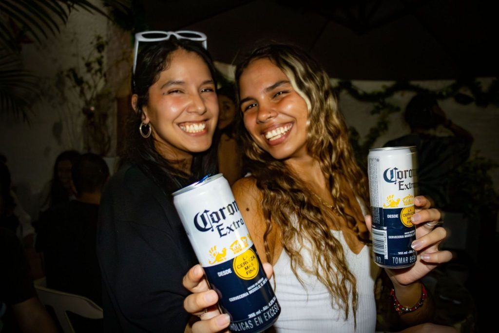 women smiling and holding cans of beer