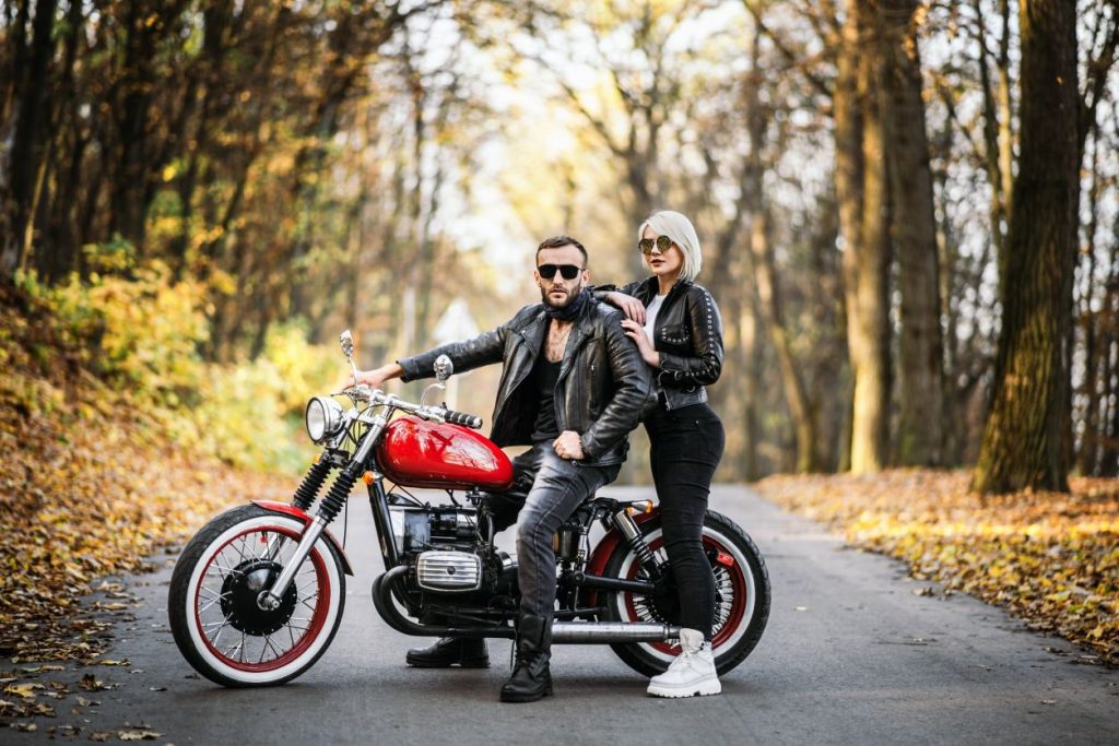 a couple in biker attire posing with their motorcycle