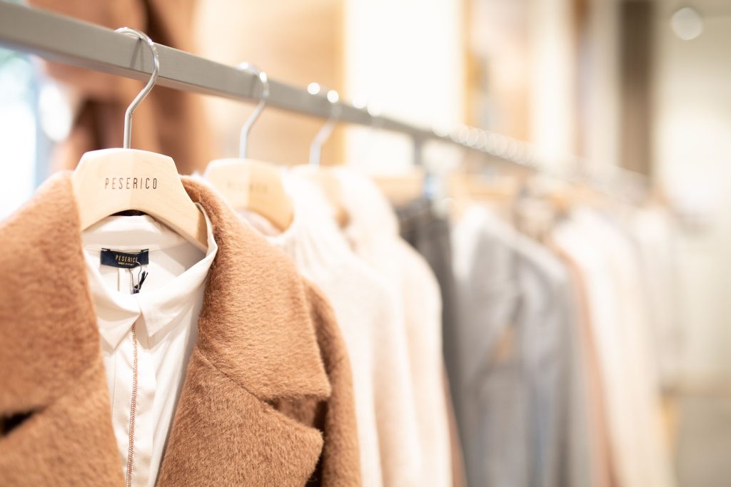 a variety of suits and other clothes hanging on a rack in a store