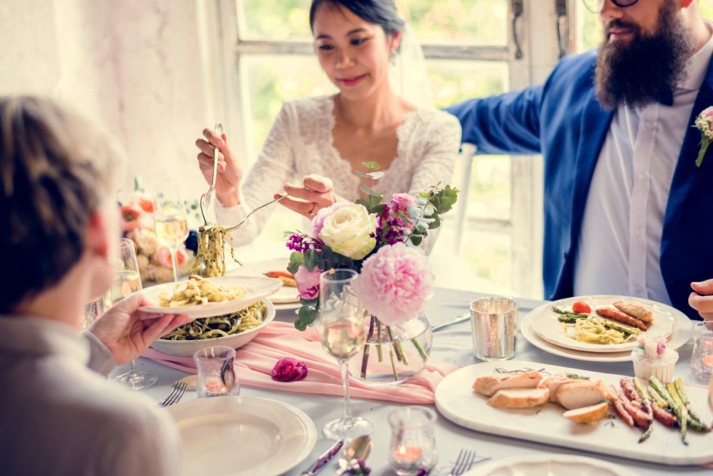 bride and groom serving pasta to a guest