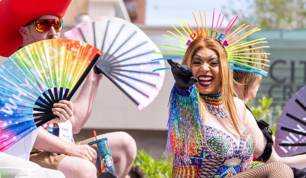 drag queen waving to a crowd at a pride parade