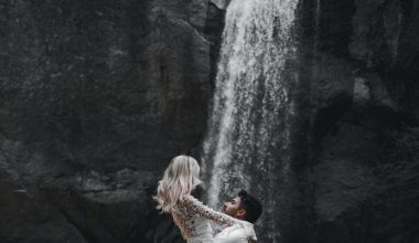 man carrying a woman near a waterfall