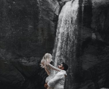 man carrying a woman near a waterfall