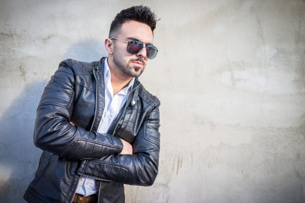 man wearing sunglasses and a black leather jacket over a white button-up