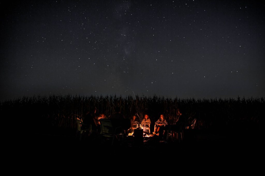 people sitting around a campfire under a starry sky