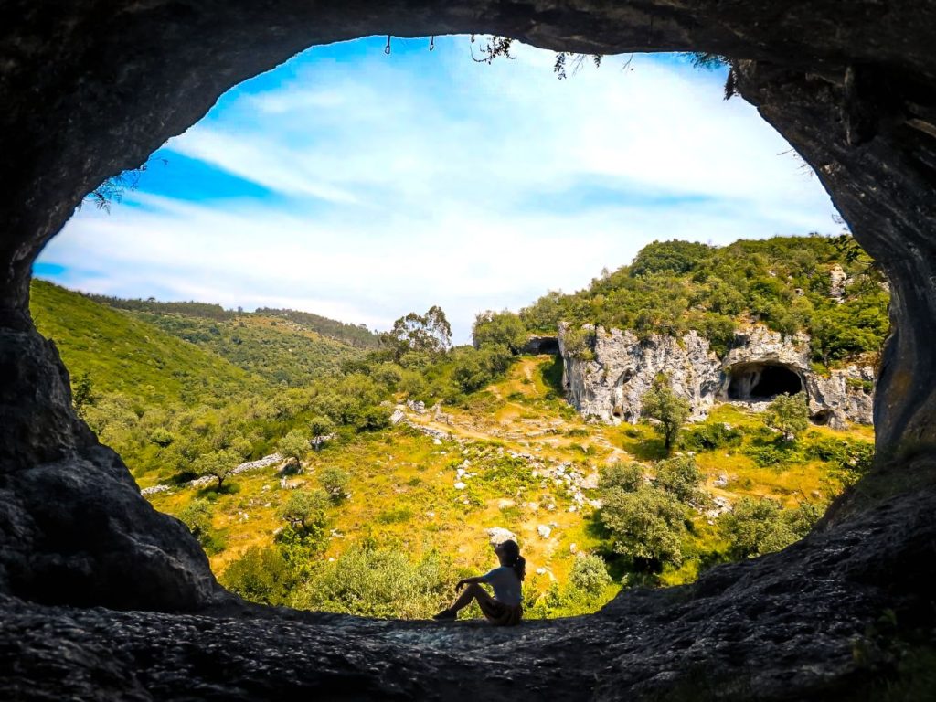 woman sitting on the entrance of a cave