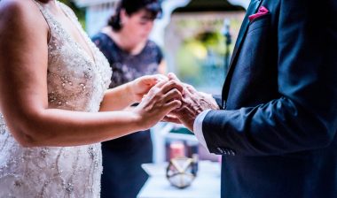 couple putting on rings during wedding ceremony
