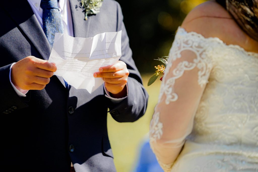 groom holding a piece of paper while exchanging vows with bride