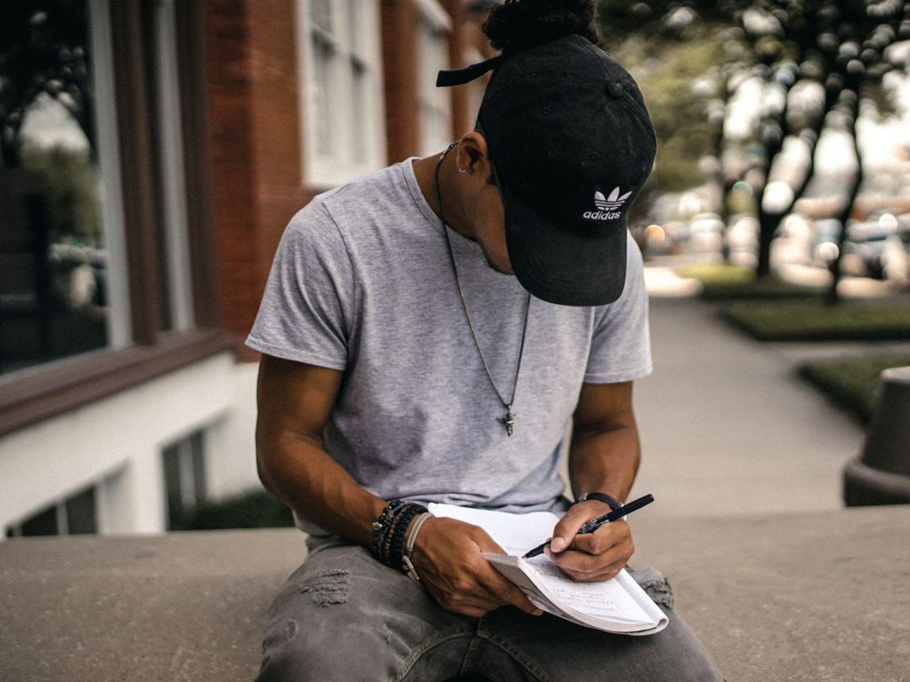 man in casualwear writing on a notebook