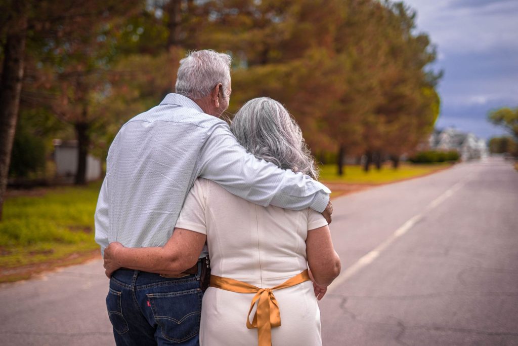 older couple standing on a road while embracing