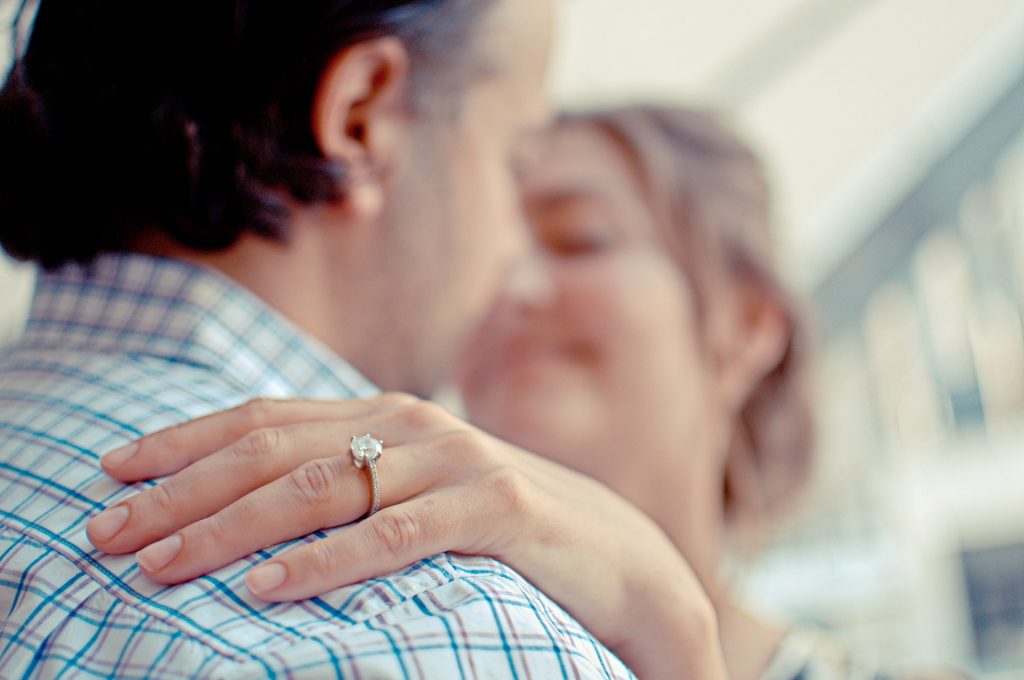 couple embracing with focus on womans engagement ring