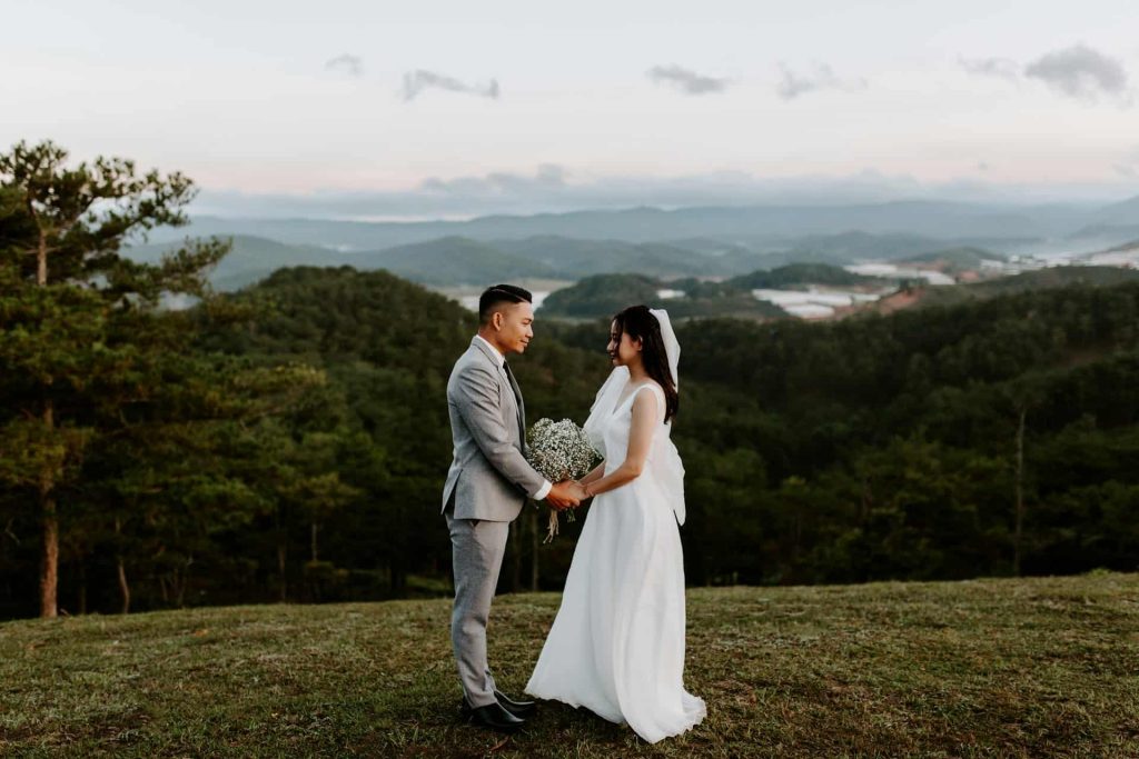 couple in wedding attire holding hands exchanging spanish wedding vows with view of hills