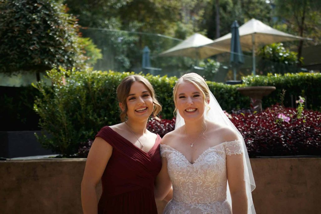 maid of honor and bride smiling and posing for a picture